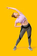 © Pixel-Shot - Sporty young woman doing side bend on yellow background