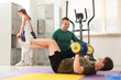 © Pixel-Shot - Male coach training young man with dumbbells in gym