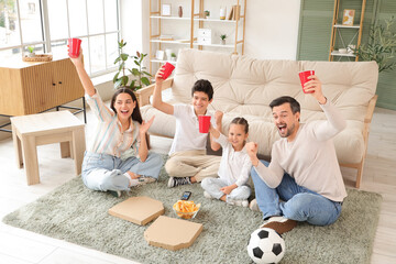 Wall Mural - Happy family with soccer ball, drinks and snacks watching football game at home