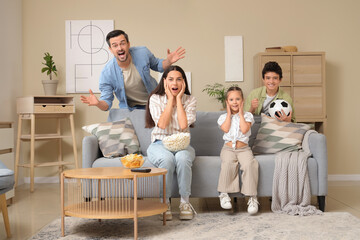 Wall Mural - Happy family with snacks and soccer ball watching football game at home