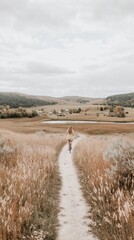 Canvas Print - A woman walking down a path in a field