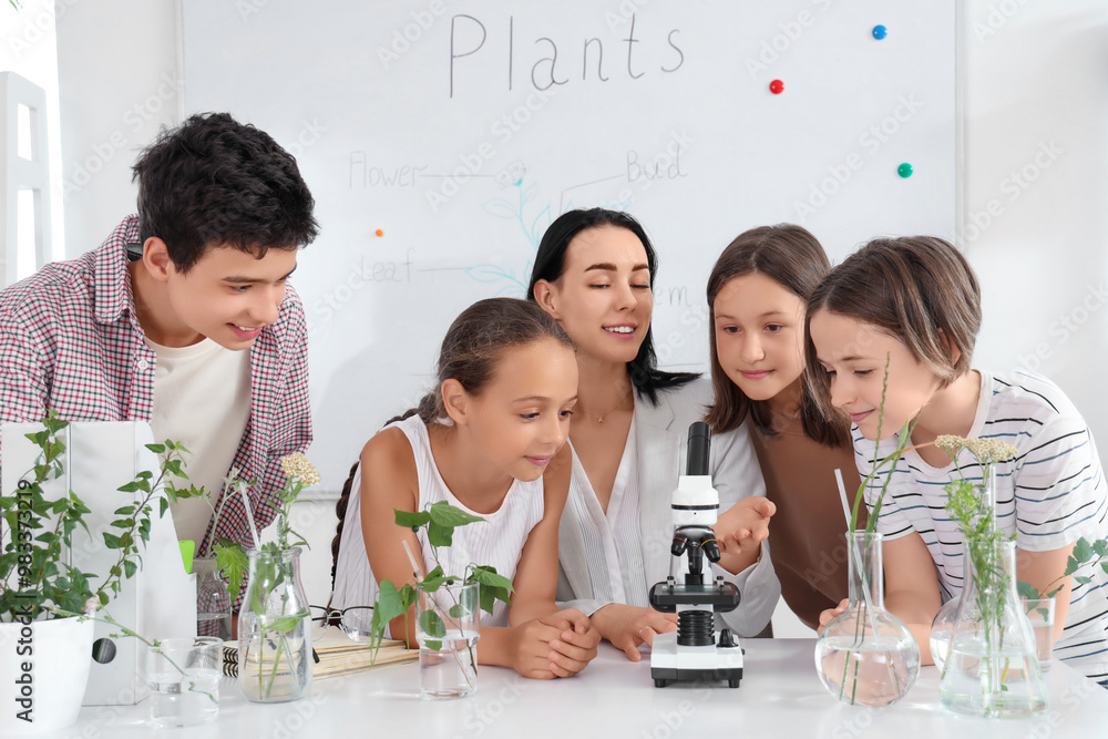 Pupils with teacher and microscope studying in Biology class
