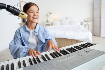 Wall Mural - Singing little girl with microphone playing synthesizer in bedroom