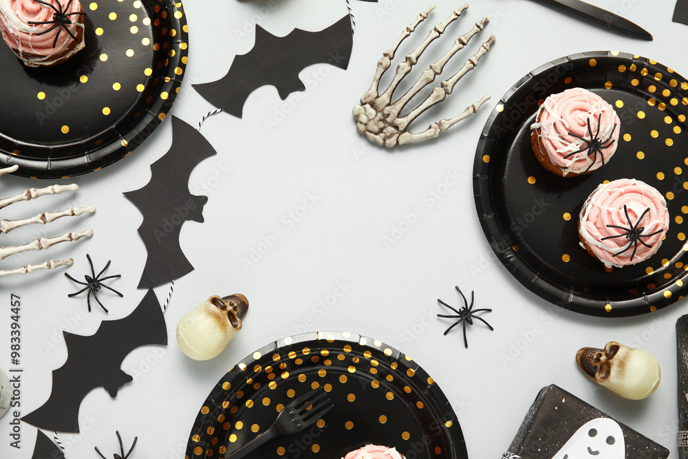 Frame made of decorations, cakes and tableware for Halloween party on light background