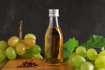 Wall Mural - Bottle of cosmetic grape seed oil on black background