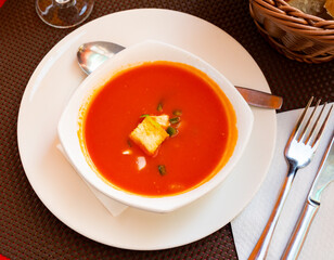 Traditional cold soup gazpacho served with vegetables, squabs, peppers and baked breads in plate. Spanish cuisine