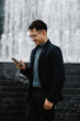 © Kritdanai - Urban Oasis Connection: Young Professional Finds Joy in Mobile News by Fountain