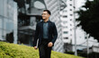 © Kritdanai - Urban Commute, Confident Future: Young Asian professional strides through city with laptop, ambition in his stride.