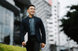 © Kritdanai - Confidently Striding Towards Success: A young, successful Asian businessman walks confidently through the bustling city streets, exuding an aura of ambition and determination. His confident stride and