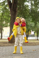 Wall Mural - Happy children with raincoats in park on rainy autumn day