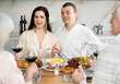© JackF - Glad young man and woman having conversation and drinking wine sitting at table with their old family members at home