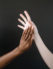 Two hands of different skin tones gently touch, symbolizing unity, diversity, and human connection against a dark background.