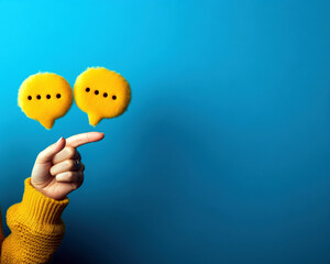 A hand pointing at two yellow speech bubbles on a blue background. The speech bubbles are crossed, and the hand is pointing to the left one