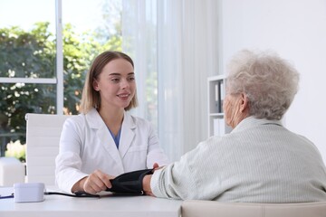 Canvas Print - Doctor measuring patient's blood pressure at table in hospital