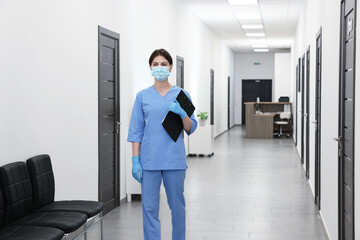 Nurse in uniform with clipboard in hospital hallway