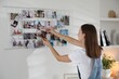 © New Africa - Woman creating vision board with different photos indoors