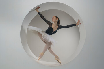 young ballerina in a white tutu poses standing in a ring set. A beautiful ballerina in a circle