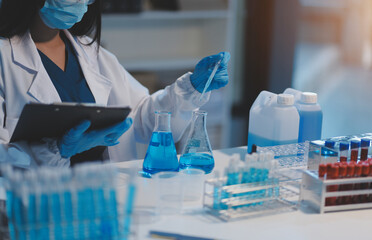 Group of dedicated scientist conduct chemical experiment in medical laboratory, carefully drop precise amount of liquid from pipette into test tube for vaccine drug or antibiotic development. Neoteric