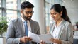 © N7 - 'Indian HR Manager with Recruitment Documents' - An Indian HR professional holding recruitment documents and discussing with a colleague.