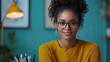 © nddcenter - Confident & Creative: A young Black woman with glasses and a warm smile exudes confidence in her vibrant home office.