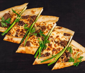 Traditional turkish pide with cheese and meat on black wooden table