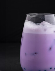 Refreshing iced taro bubble tea in glass on black background