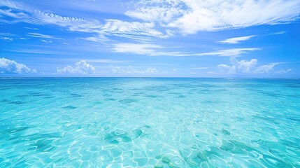 A beautiful scene of the blue ocean against the blue sky background. The ocean stretches out as far as the eye can see, with its surface glistening in the sunlight