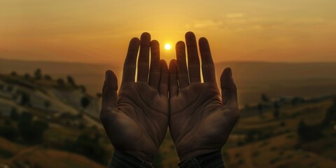 A silhouette of hands reaching towards a radiant sunrise, set against the backdrop of a mountainous landscape.