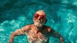 © Tamara - Elderly man enjoying a sunny day in a pool with vibrant red sunglasses, creating a joyful and carefree atmosphere.