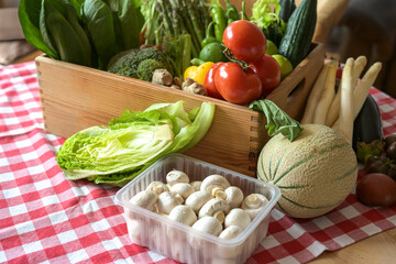 Various fresh vegetables in a wooden box on a red checkered tablecloth, concept for agriculture and healthy food