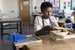 © ReeldealHD images - African American boy learning carpentry in woodworking class at school