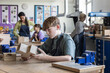 © ReeldealHD images - Boy student looking at his project in woodworking class at school