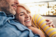 © baranq - Portrait of happy couple hugging lying on the sofa at terrace