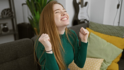 Poster - Laughing young woman with blonde hair enjoying a relaxed moment in a modern living room.