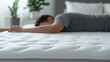 © Oulaphone - A person lies face down on a mattress, suggesting relaxation or sleep in a serene bedroom environment with plants nearby.