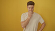 © Krakenimages.com - A young hispanic man stands pensively against an isolated yellow background, exuding an attractive and thoughtful demeanor.