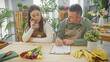 © Krakenimages.com - A man and woman, likely colleagues, collaborate at a flower shop, with the woman on a phone call and the man writing notes.