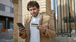 © Krakenimages.com - Young hispanic man with beard using smartphone and credit card on urban street.