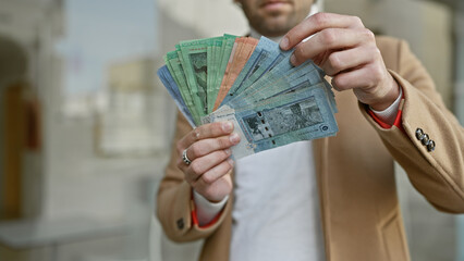 Sticker - Handsome bearded man holding malaysian ringgit with city street background, portraying financial concept in an urban setting.