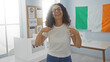 © Krakenimages.com - Woman smiling indoors in an electoral college room with an irish flag, pointing to herself with voting signs in the background, conveying a message of pride and civic duty.