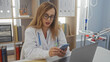 © Krakenimages.com - Middle-aged female doctor with blonde hair using a smartphone in her clinic workplace