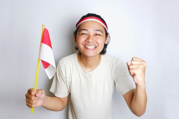 Portrait of an Indonesian man with long hair with a headband and red shirt celebrating Indonesian Independence Day with high nationalism on an isolated white background