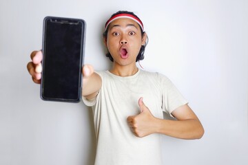 Portrait of an Indonesian man with long hair with a headband and red shirt celebrating Indonesian Independence Day with high nationalism on an isolated white background