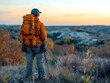 © AIGC JOE - A man stands on a hilltop at sunset, taking in the view. He is wearing a bright orange jacket and carrying a large backpack.