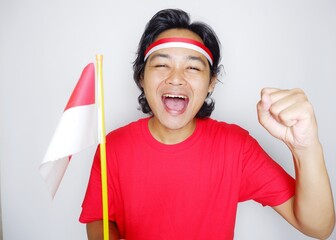 Portrait of an Indonesian man with long hair with a headband and red shirt celebrating Indonesian Independence Day with high nationalism on an isolated white background