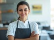 © vefimov - A professional woman chef smiling in a restaurant kitchen, wearing an apron.