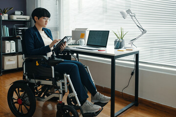 Wall Mural - Asian office worker with disability working on tablet pc in office