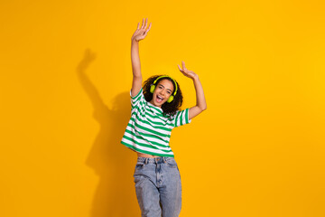 Wall Mural - Portrait of nice young girl dance headphones music wear striped t-shirt isolated on yellow color background