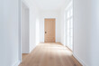 © dK - Bright minimalist hallway with natural light and a wooden door, featuring clean white walls and light hardwood flooring, creating a modern and spacious interior design