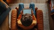 © GoodandEvil - Boy in yellow shirt holding tablet in brown armchair.